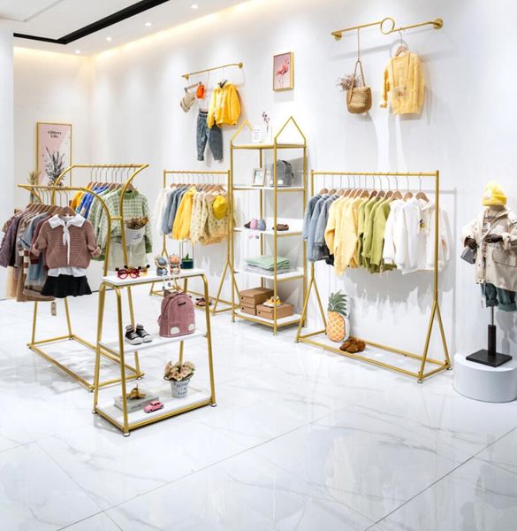 Children's clothing store display with golden shelves and baby hangers in a kids' shop