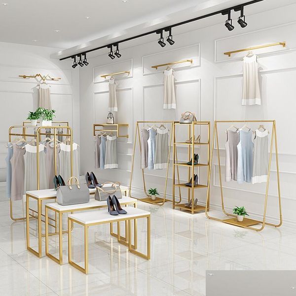 Gold clothing store display rack for bedroom furniture, featuring wall-mounted women's cloth hangers and floor-standing racks